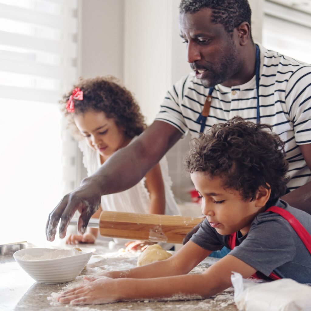 A black male father cooking with his children